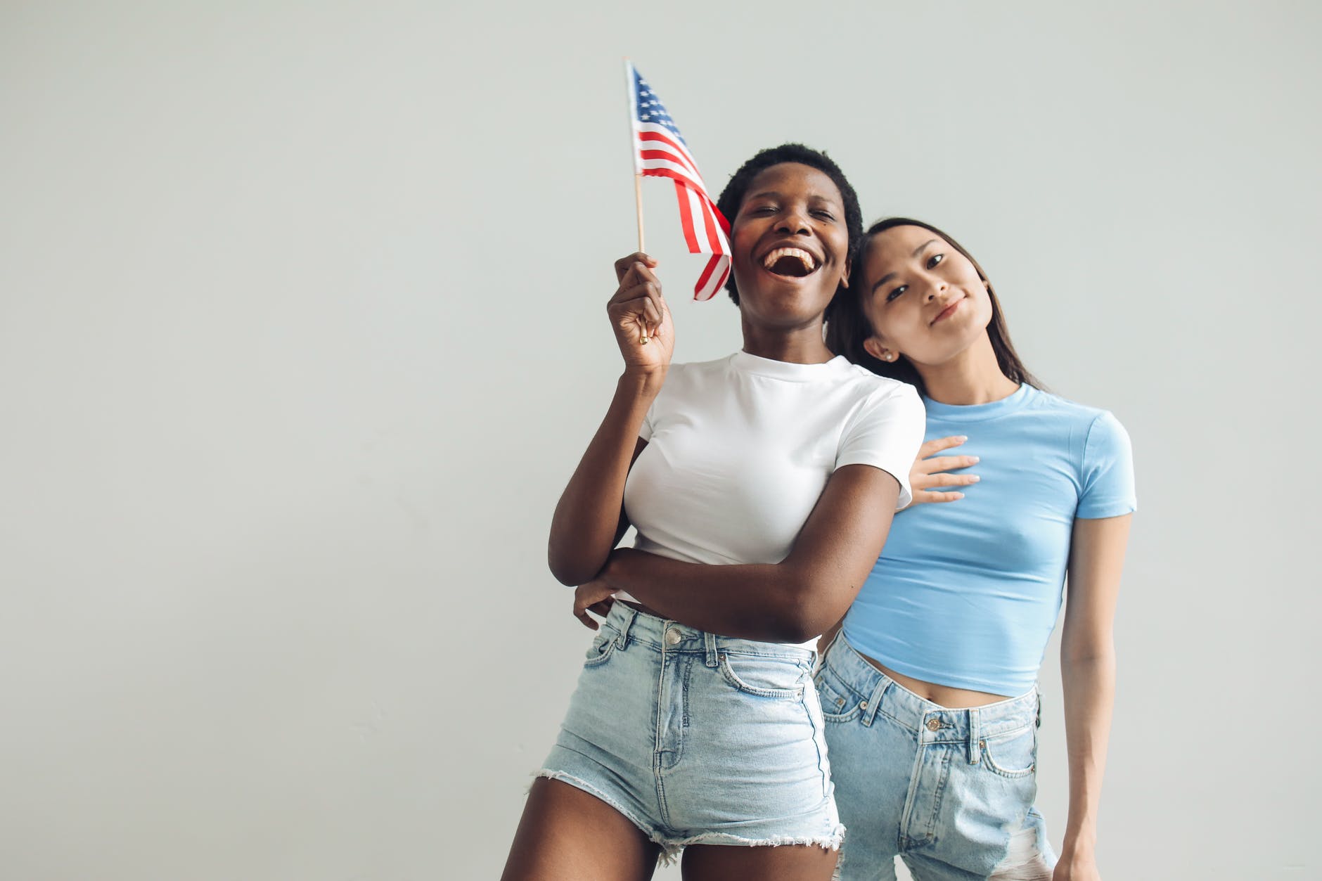 woman in white shirt and blue denim shorts holding a flag