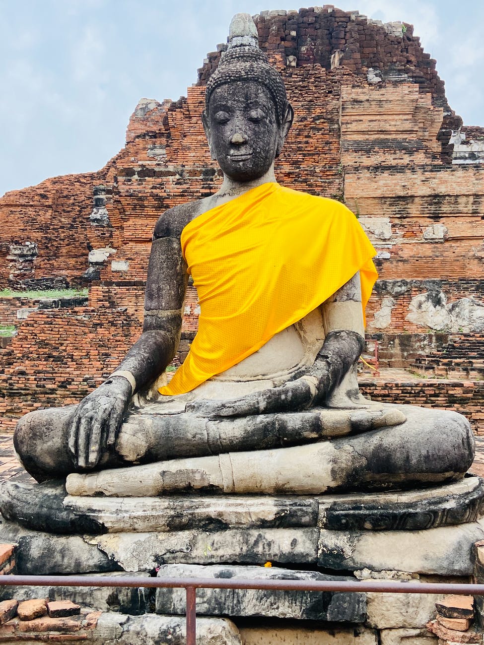 man in yellow shirt sitting on concrete statue