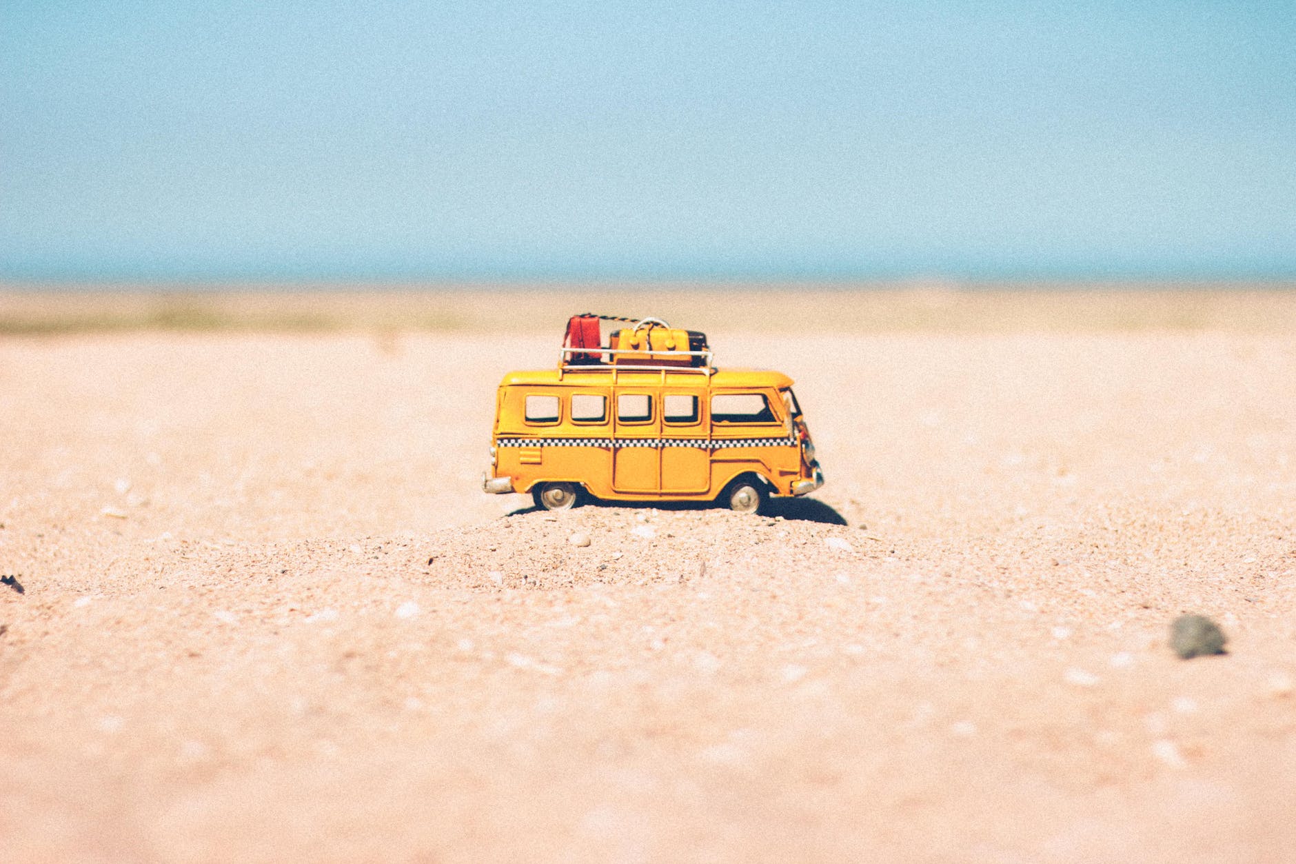 yellow die cast miniature van on brown sand