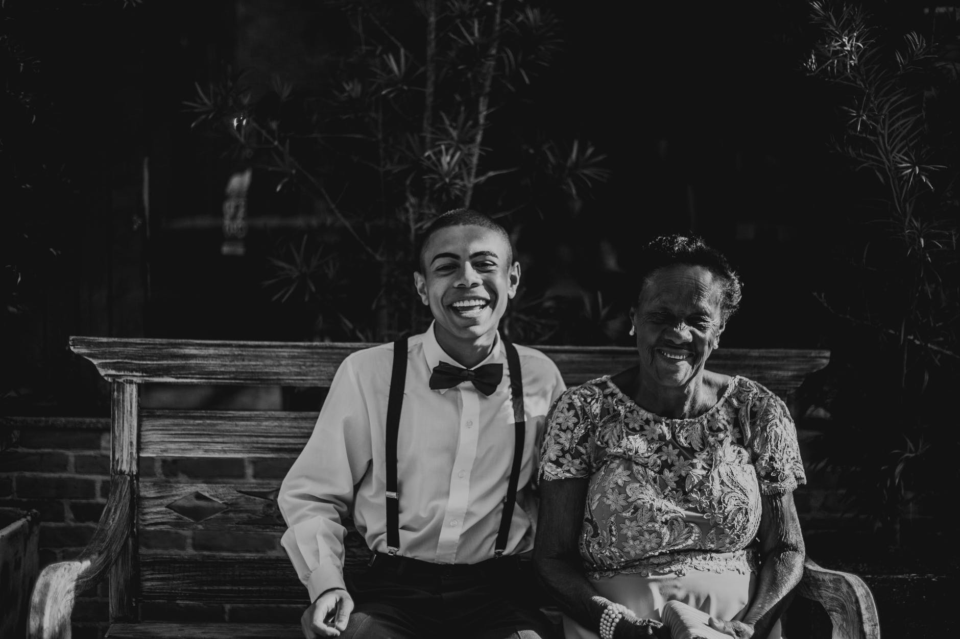 man and woman sitting on bench in grayscale photography